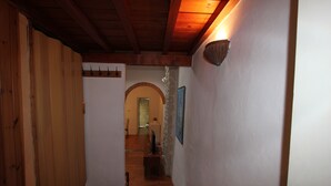 A narrow hallway with wooden walls and a tiled floor, leading to a room with a stone archway. - Oltrarno Loft (Florence)