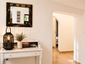 Une console blanche, ornée d’un miroir, d’une lanterne et d’une plante en pot.