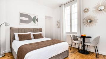 Una camera da letto moderna con un letto, una lampada da comodino e un piccolo tavolo con sedie.