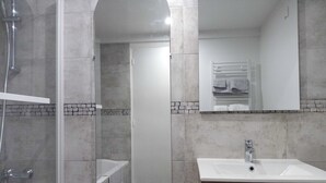 Une salle de bain avec une douche, un lavabo et un miroir.