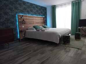 Ein Schlafzimmer mit einem hölzernen Kopfteil, einem Bett mit weißer Bettwäsche, grünen Kissen und einem kleinen Nachttisch.