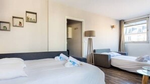 Ett hotellrum med två sängar, ett skrivbord och en lampa.