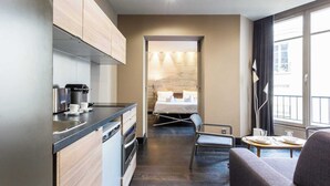 Une chambre d’hôtel moderne dotée d’une kitchenette, d’un coin repas et d’un lit avec vue.
