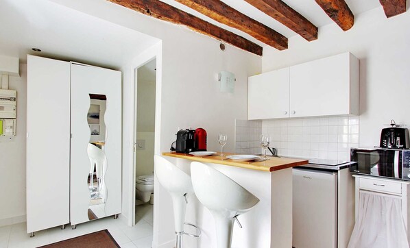Une cuisine moderne avec des meubles blancs, un plan de travail en bois et une machine à café.