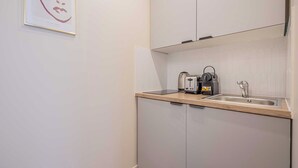 A small kitchenette with a sink, a kettle, and a toaster. - Cosy Studio for 2P - Le Bon Marche (Paris)