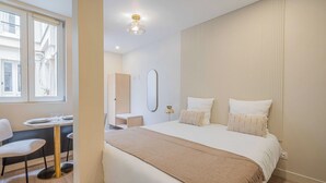 A modern hotel room with a large bed, a round dining table, and a chair. - Cosy Studio for 2P - Le Bon Marche (Paris)