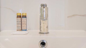 A bathroom sink with two bottles of shampoo and a glass container. - Cosy Studio for 2P - Le Bon Marche (Paris)