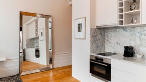 Una cocina moderna con armarios blancos, encimera de mármol y un espejo grande.
