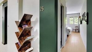 A hallway with a green door marked with the number 26, leading to a room with a bed and a chair. - Modern "green Suites" Residence - Meudon/velizy (Meudon)