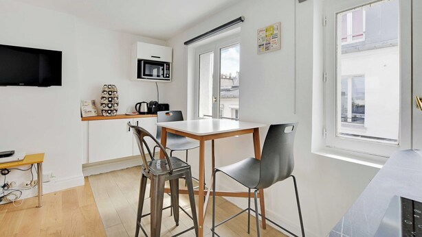 A compact kitchen with a microwave, a coffee machine, and a small dining table with chairs. - Charming Studio for 2 People - Bastille (Paris)