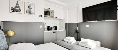 Habitación de hotel con cama, mesita de noche, lámpara, microondas, televisión y dos cuadros en la pared.