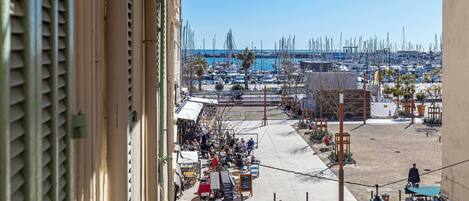 A balcony with a view of a marina, outdoor seating area, and a clear sky.