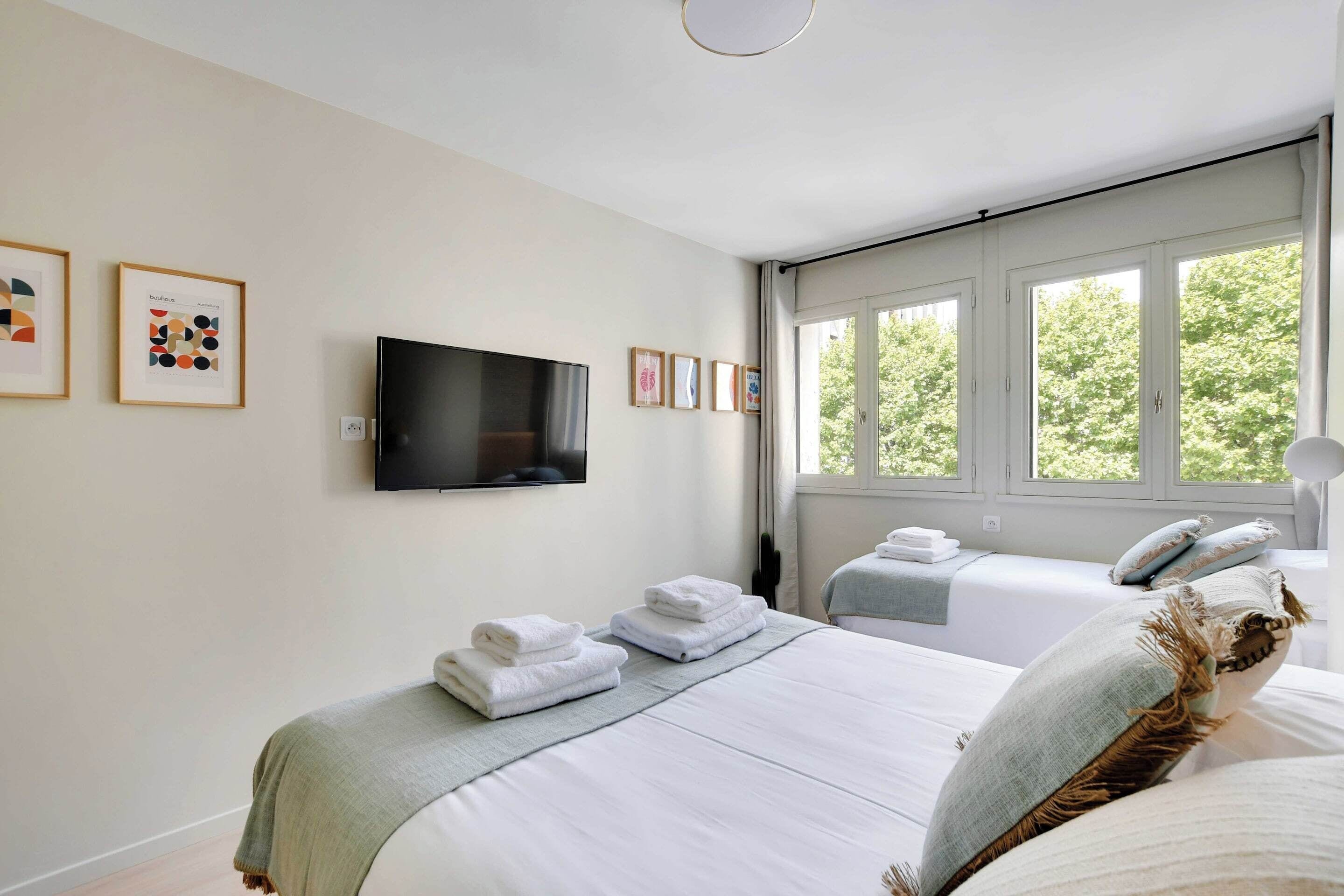 Une chambre d’hôtel avec deux lits, un téléviseur à écran plat et des œuvres d’art accrochées aux murs.