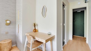 A modern room with a wooden desk, a white chair, a small round table, a vase with dried flowers, and a wall-mounted mirror. - Modern "green Suites" Residence - Meudon/velizy (Meudon)