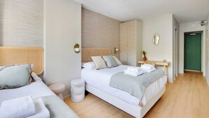 A modern hotel room with two beds, a small desk, a mirror, and a green door in the background. - Modern "green Suites" Residence - Meudon/velizy (Meudon)