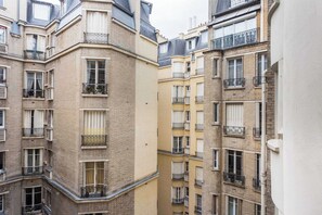 A multi-story residential building with balconies, large windows, and a brick facade. - Charming Apartment - 1br/4p - Passy (Paris)