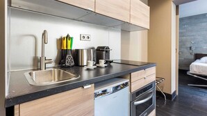 A modern kitchen with stainless steel appliances, wooden cabinets, and a black countertop. - Charming Apartment - 1br/4p - Passy (Paris)