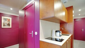 A compact kitchen with a pink cabinet, a small countertop, and a coffee maker. - Charming Studio - 2P - Republique/oberkampf (Paris)