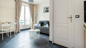Ein Zimmer mit einer weißen Tür, einem schwarz-weiß karierten Sofa, einem kleinen runden Tisch und einem weißen Stuhl.