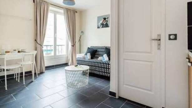 Ein Zimmer mit Esstisch, Stühlen, einer Couch, einem kleinen runden Tisch und einer Tür.