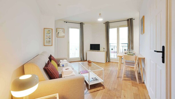 Ein modernes Wohnzimmer mit einer Couch, einem Couchtisch und einem Fernseher auf einem weißen Schrank.
