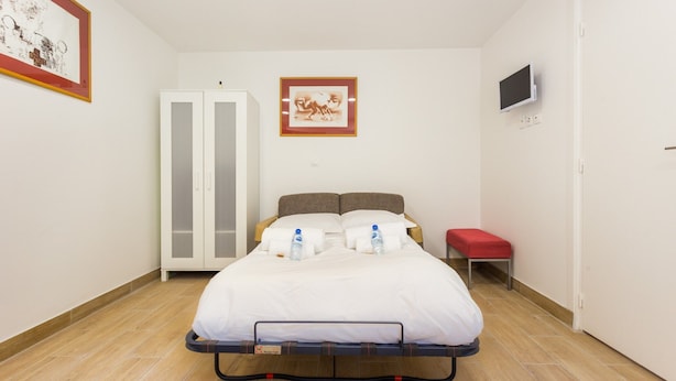 A bedroom with a bed, a wardrobe, a television, and a framed picture on the wall. - Elegant Studio - 2P - Malakoff (Malakoff)