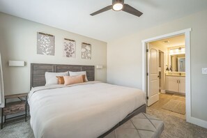 A bedroom with a bed, a ceiling fan, and a door leading to a bathroom. - Spacious 9BR 9BA Combined Condos in Traverse City (Williamsburg)