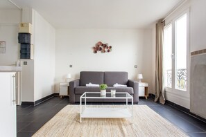 A modern living room with a grey sofa, a white coffee table, and a decorative wall piece. - Magnificent Studio - 2P - Pantin/edouard Vaillant (Pantin)