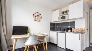 Een kleine keuken met een eethoek, een televisie en een decoratief wandobject.