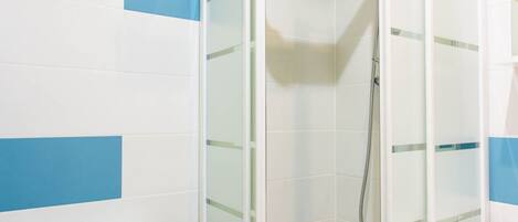 Een moderne badkamer met een douchecabine van glas, een wit toilet en een witte wastafel.