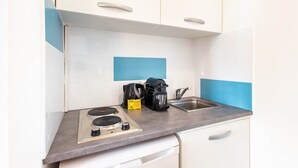 A compact kitchen with a gas stove, coffee maker, and a sink. - Magnificent Studio - 2P - Moulin Rouge (Paris)