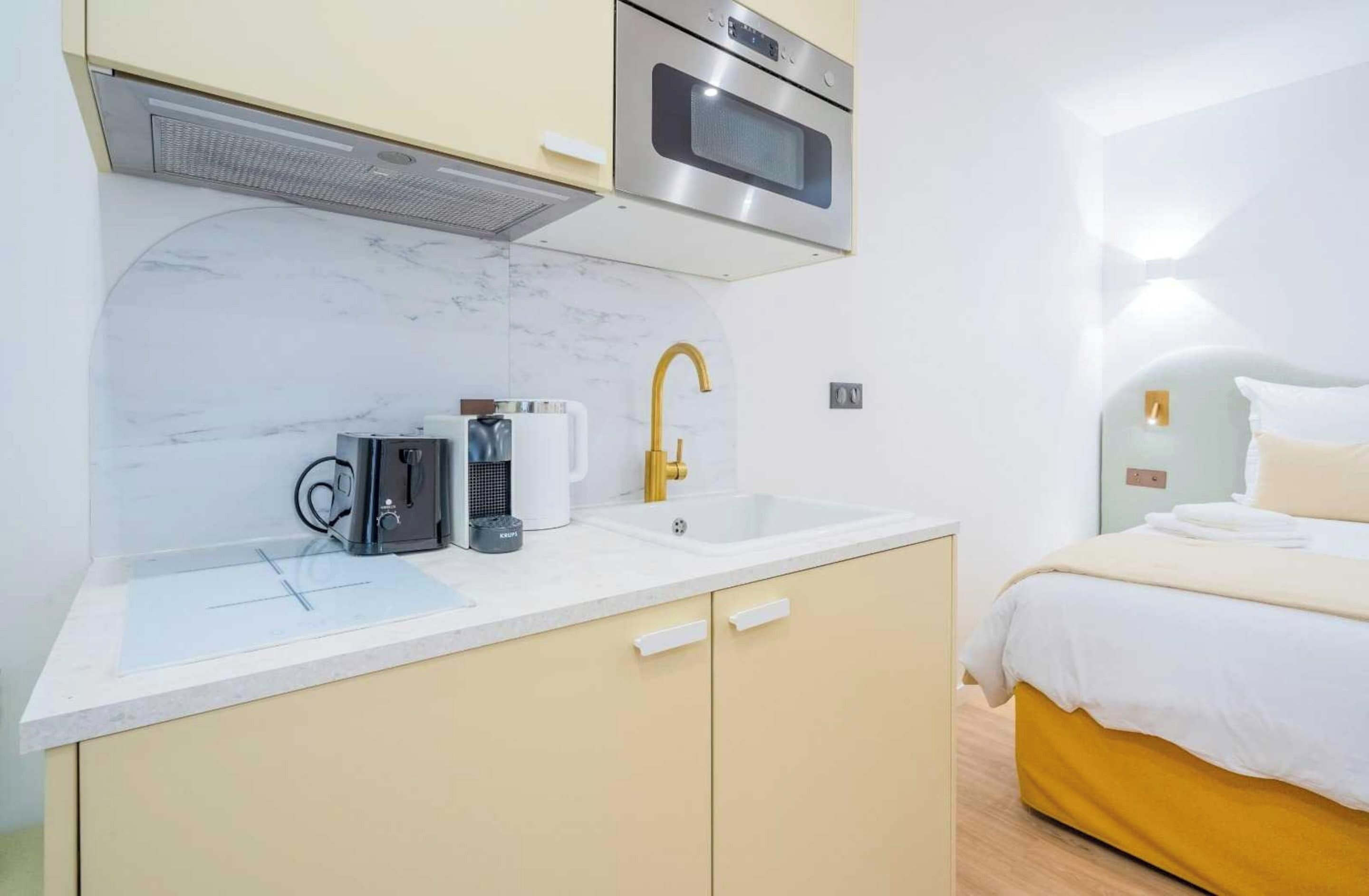 A compact kitchenette with a microwave, coffee maker, and sink.
