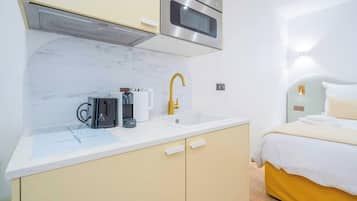 A compact kitchenette with a microwave, coffee maker, and sink.
