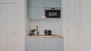 Een kleine keuken met een magnetron, koffiezetapparaat en spoelbak.