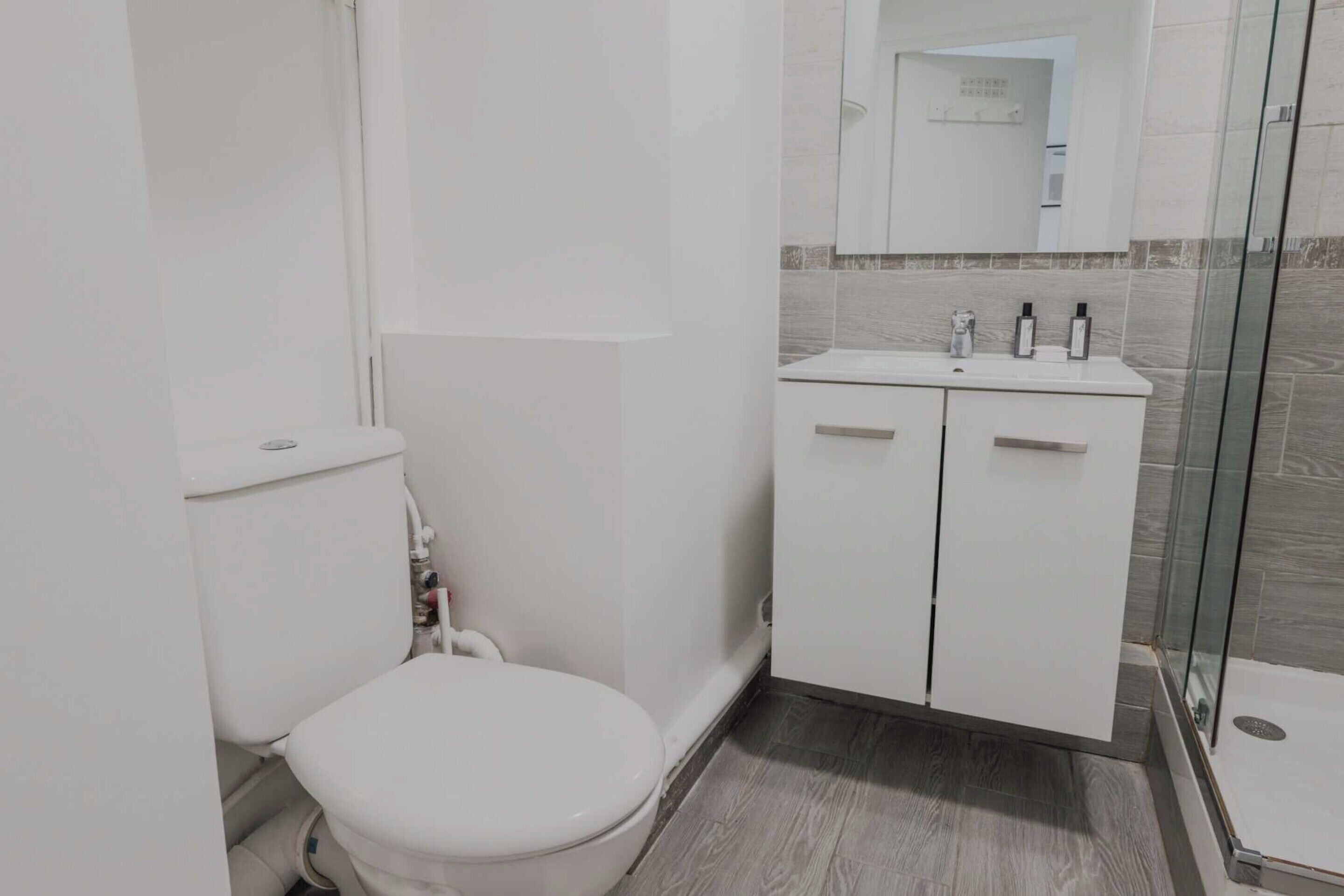 A compact bathroom with a toilet, a sink, and a shower area.