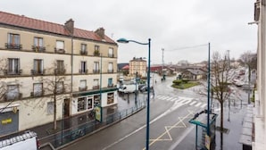 Une vue de rue avec des bâtiments, un passage piéton et un lampadaire bleu.