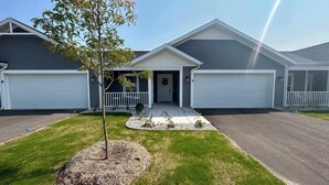A two-story house with a front porch, a garage, and a driveway. - Spacious 10BR 10BA Combined Condos in Traverse City (Williamsburg)