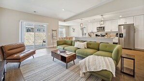 Ein modernes Wohnzimmer mit einem grünen Sofa, einem braunen Ledersessel und einem Holztisch.