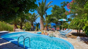 A swimming pool with a stone deck, surrounded by lounge chairs and a small gazebo. - Villa Ginestra, Scopello (CASTELLAMMARE DEL GOLFO)