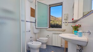 Kylpyhuoneessa on bidee, wc, pesuallas ja ikkuna, josta avautuu näkymä vuoristomaisemaan.