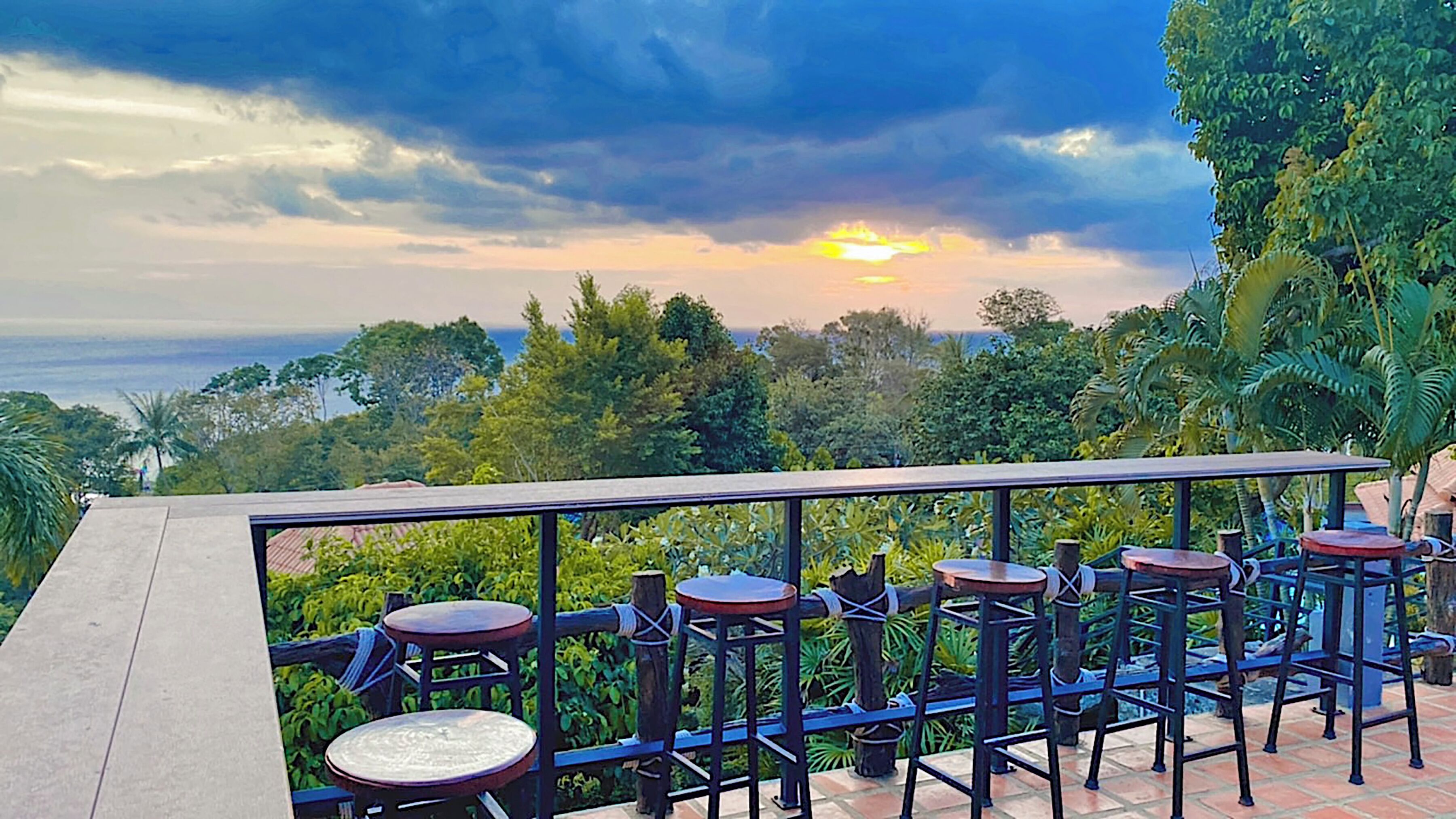 A terrace with outdoor seating and a scenic view of the ocean and hills.
