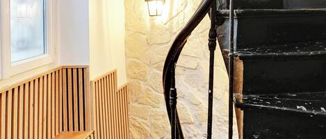 A spiral staircase with black railings and a stone wall.