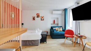 A modern hotel room with a bed, a sofa, a dining table, and a TV. - Stunning Studio for 2 People - Sentier (Paris)