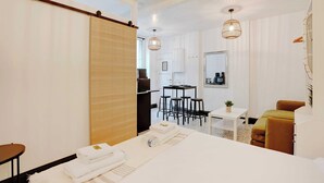 A modern hotel room with a bed, a desk, a chair, and a small table. - Cosy Studio - 2P - Place de la Bastille (Paris)