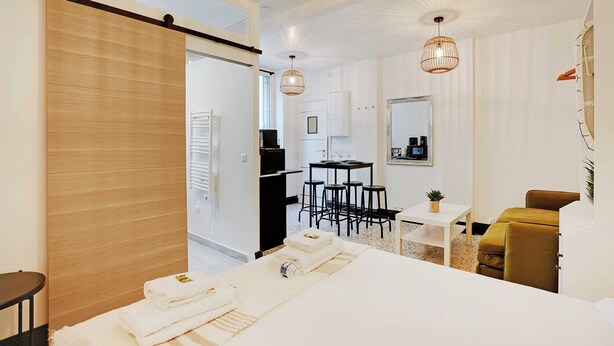 A modern hotel room with a bed, a desk, and a dining area. - Cosy Studio - 2P - Place de la Bastille (Paris)
