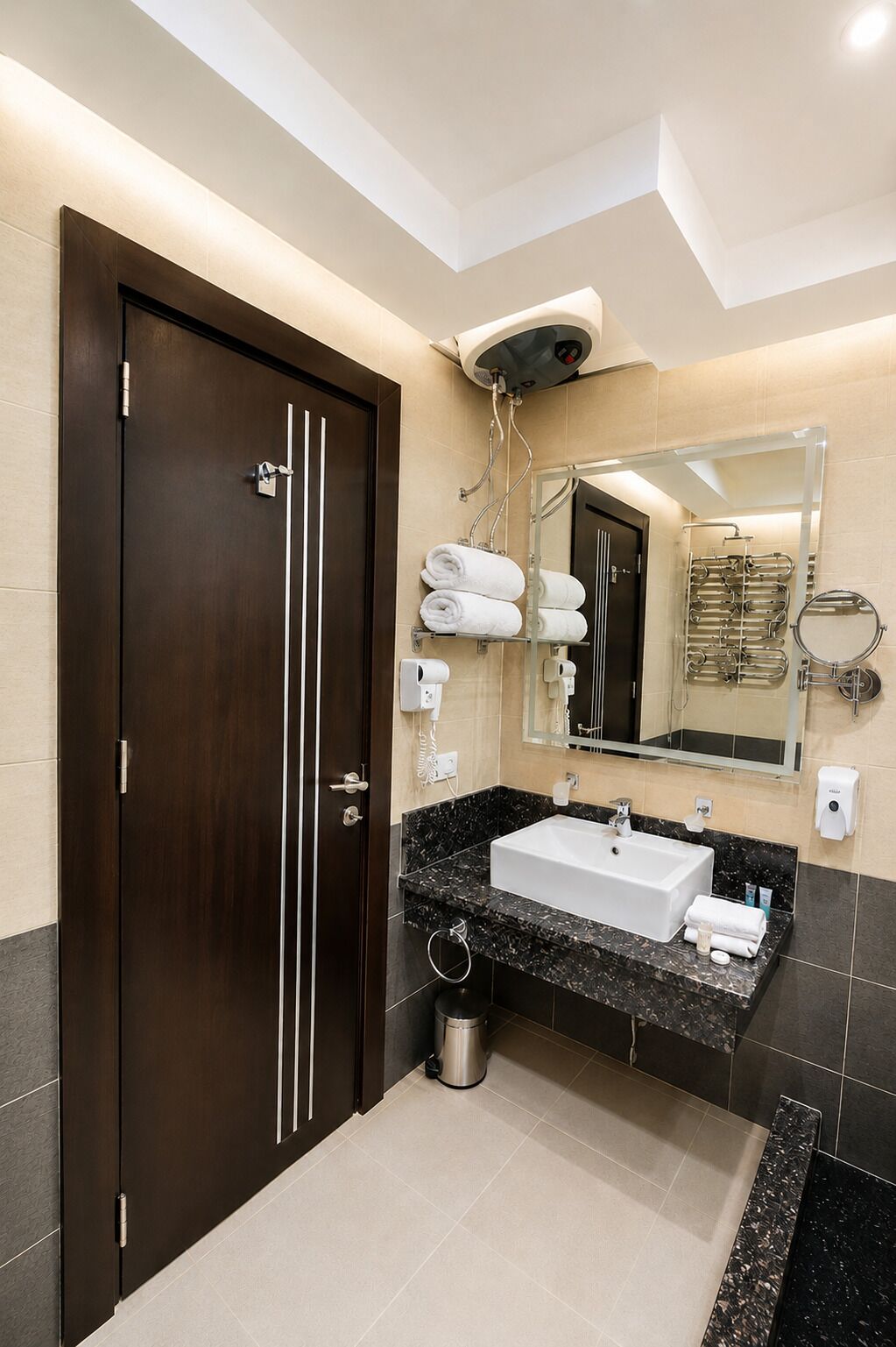 A modern bathroom with a dark wooden door, a white sink, a large mirror, and a towel rack.