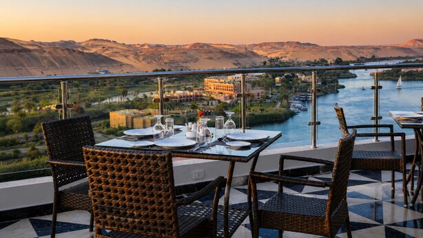 Comedor con mesas dispuestas para dos, con vistas a un río y montañas.
