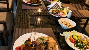 Un comedor con mesas dispuestas para comidas, que incluye carnes brochetas y platos de arroz.
