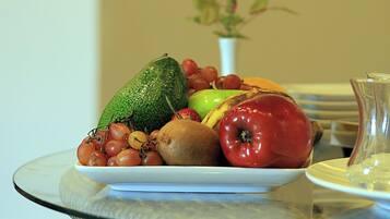 A table with a plate of fruit and a vase with a rose.