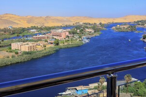 A river with buildings along its banks, a bridge, and palm trees.